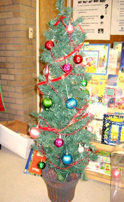 A small kids artificial Christmas  tree decorated inside an elementary school classroom