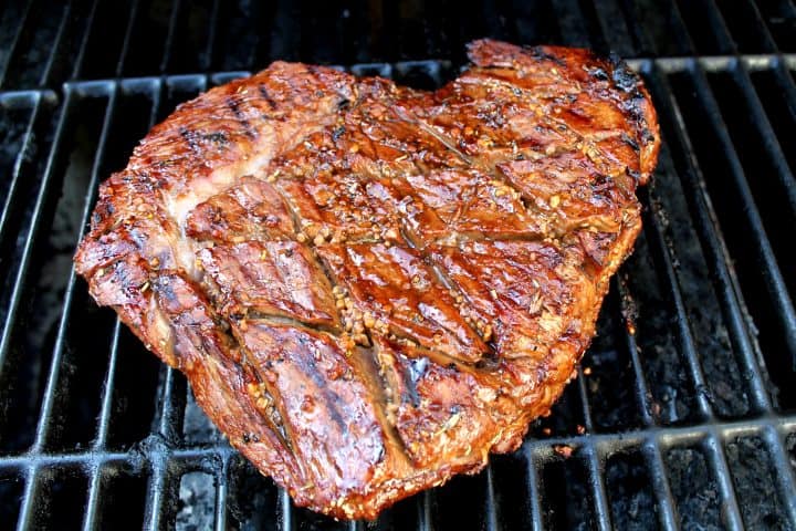 A marinated steak being cooked on a grill