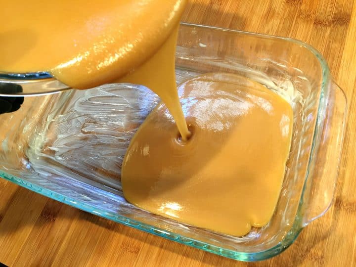 A process photo showing melted microwave caramel being poured into a buttered baking dish. The photo is part of a recipe about how to make caramel in the microwave. 