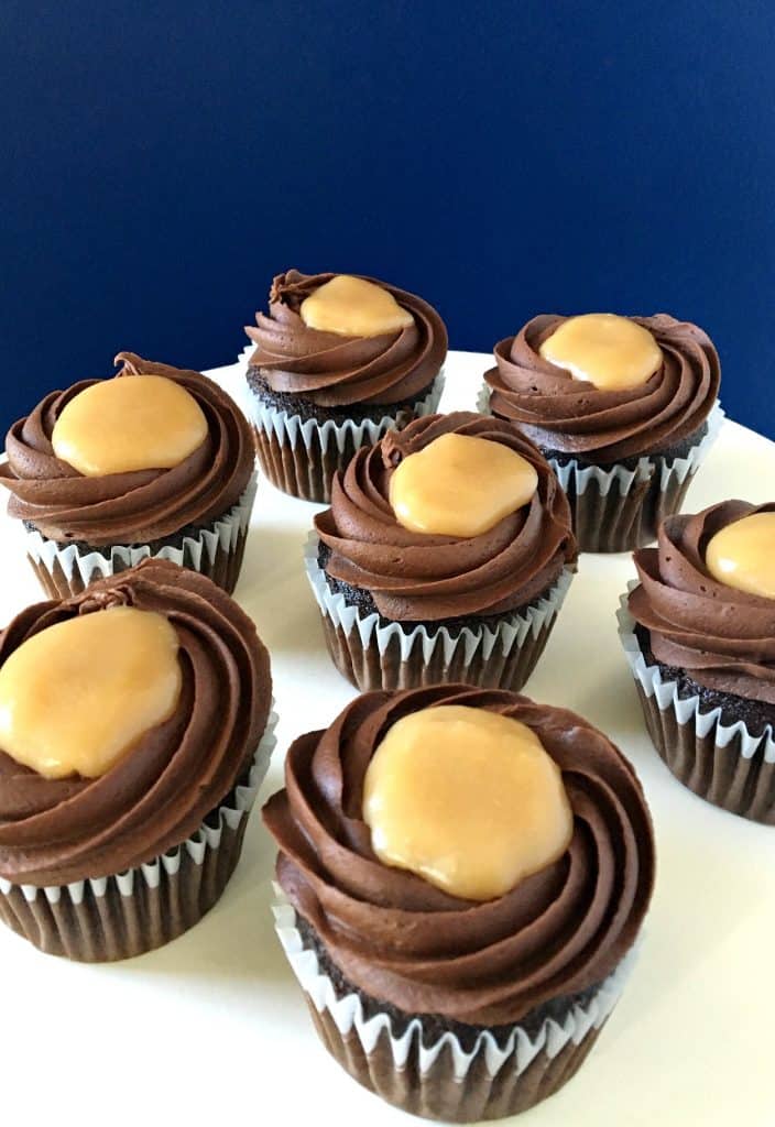 Chocolate Cupcakes with Easy Salted Caramel Centers sitting on a white plate against a blue background