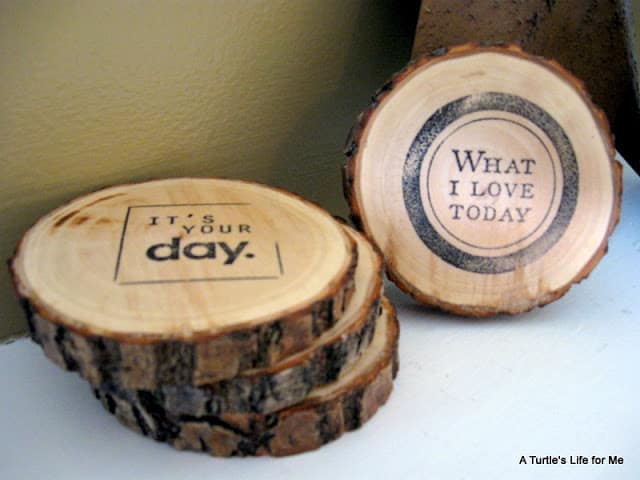 DIY wood coasters made from fallen tree branches and wooden stamps are stacked on a white table